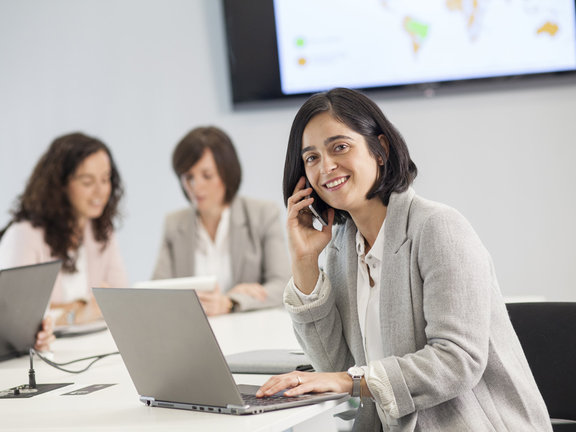 Frau, die am Telefon spricht und am Laptop arbeitet